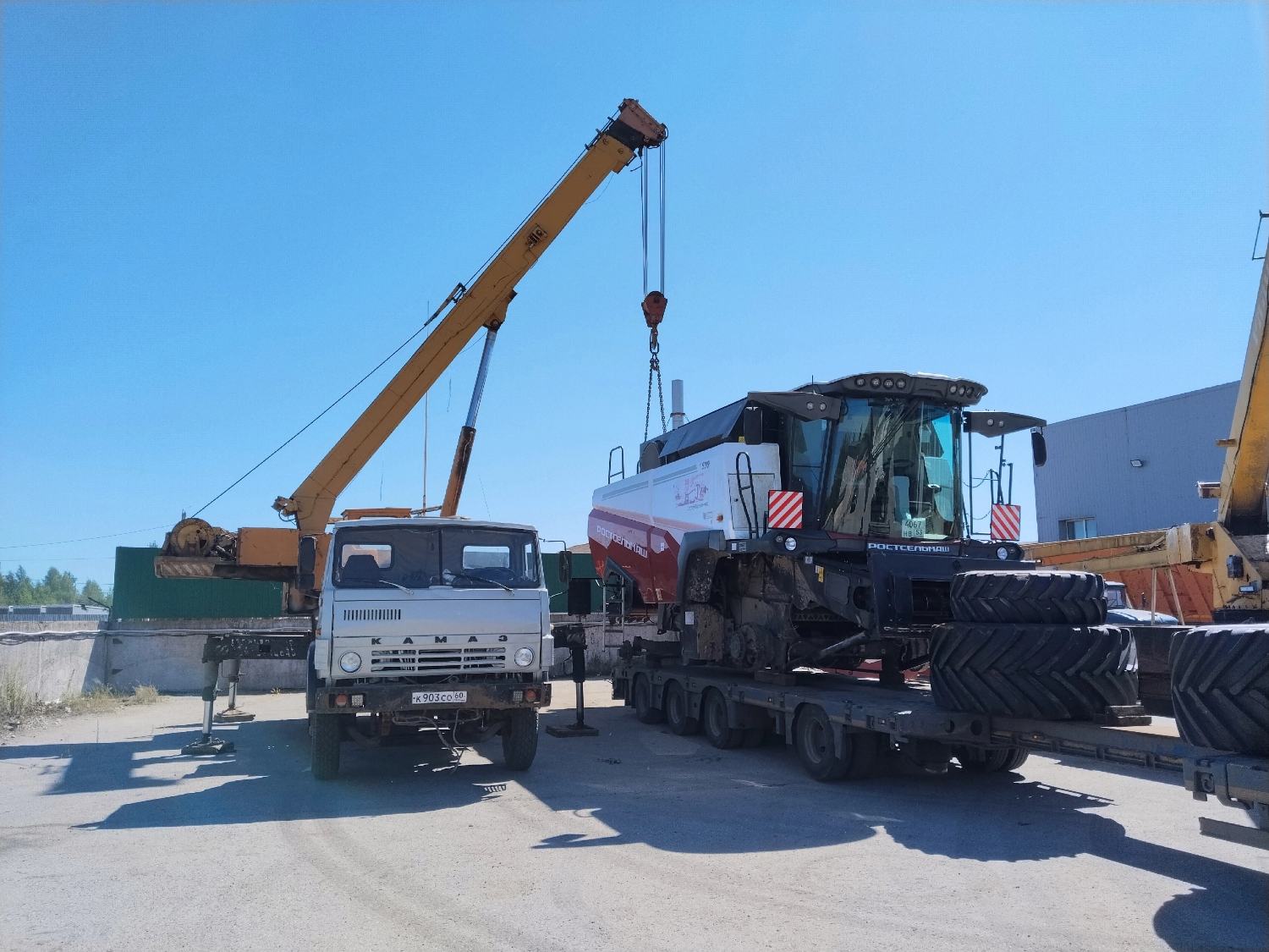 Автокран на базе КАМАЗ рядом с зерноуборочным комбайном на низкорамном трале